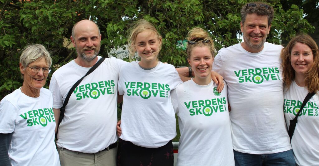 Fem personer i Verdens Skove T-shirts står samlet og smiler, et billede der passer til non-profit organisationer danmark og hvordan fællesskaber løfter naturbeskyttelse
